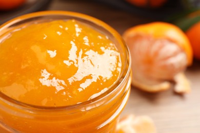 Photo of Delicious tangerine jam in glass jar, closeup