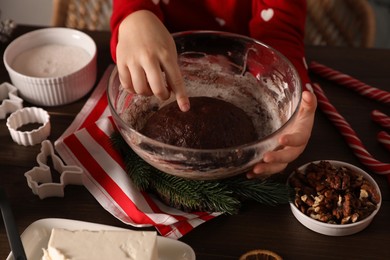 Little child making Christmas cookies at wooden table, closeup