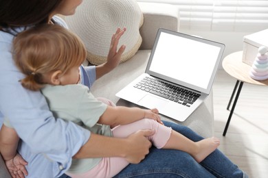 Mother and daughter with laptop on sofa at home. Pediatrician online consultation