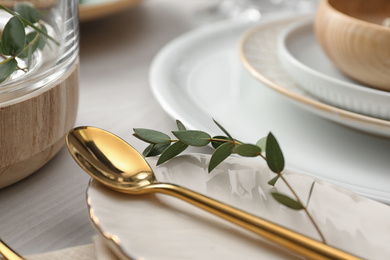 Elegant spoon with green leaves on table, closeup. Festive setting
