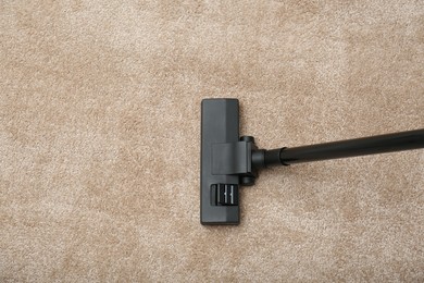 Photo of Removing dirt from carpet with modern vacuum cleaner indoors, top view