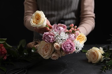 Photo of Florist making beautiful bouquet at black table, closeup
