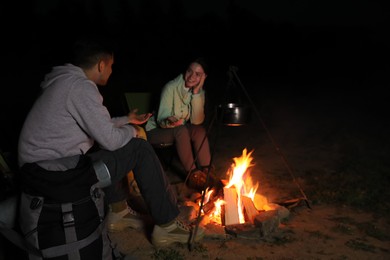 Couple near bonfire outdoors in evening. Camping season