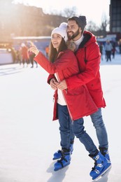 Lovely couple spending time together at outdoor ice skating rink