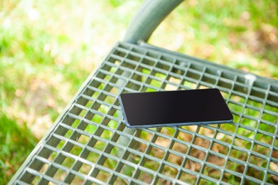 Smartphone forgotten on metal bench outdoors. Lost and found