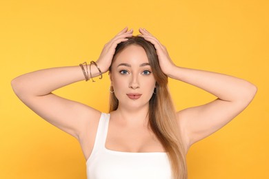 Young woman with lip and ear piercings on yellow background