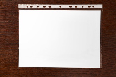Photo of Punched pocket with paper sheet on wooden table, top view
