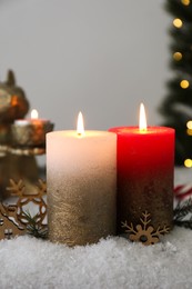 Burning candles and Christmas decor on artificial snow