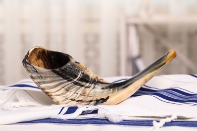 Photo of Shofar and Tallit on table indoors. Rosh Hashanah holiday attributes