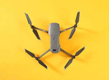 Modern drone with camera on yellow background, top view. Space for text