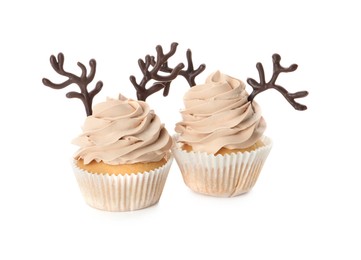 Delicious Christmas cupcakes with chocolate reindeer antlers on white background
