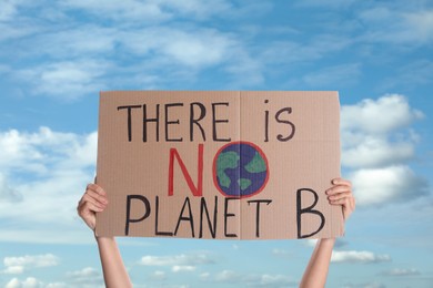 Protestor holding placard with text There Is No Planet B against blue sky, closeup. Climate strike