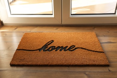 Photo of Doormat with word Home on parquet floor indoors