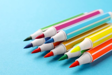 Photo of Many bright markers on light blue background, closeup