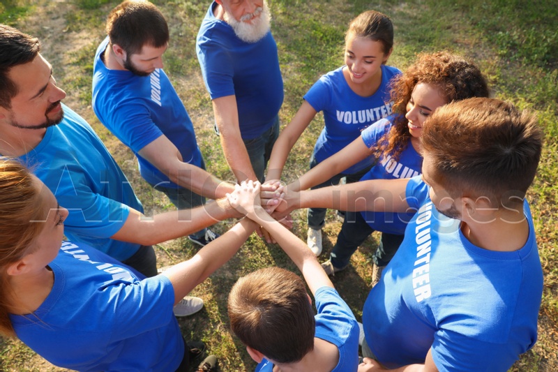 Group of volunteers joining hands together outdoors, above view