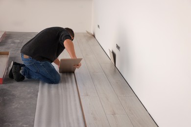 Professional worker installing new laminate flooring. Space for text