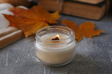 Photo of Burning scented candle on light gray textured table