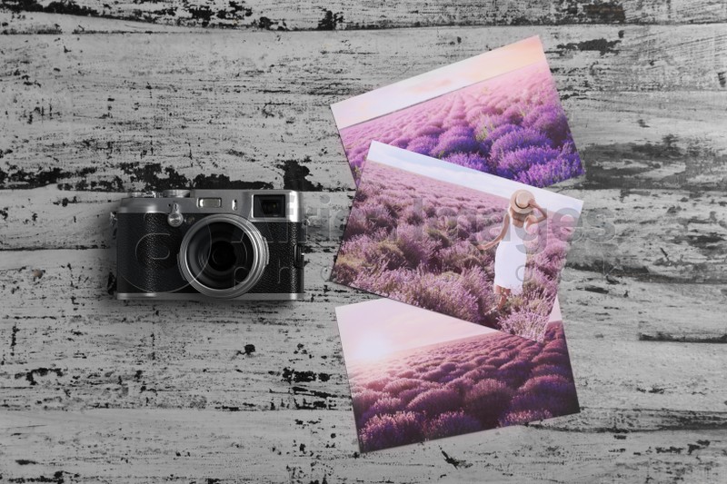 Photo of Vintage photo camera and beautiful printed pictures on rustic table, flat lay. Creative hobby