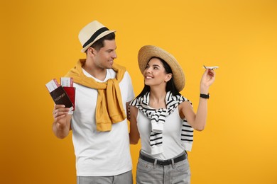 Couple of tourists with tickets, passports and toy plane on yellow background