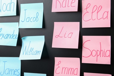Sticky notes with baby names on black board, closeup