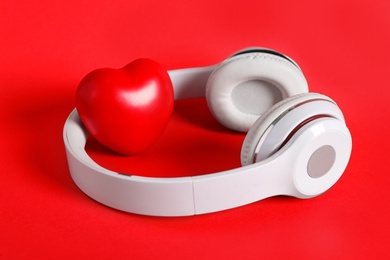 Modern headphones and heart on red background. Listening love music songs