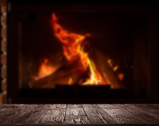 Image of Rustic table and fireplace with burning wood indoors