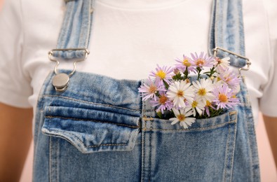 Woman with beautiful tender flowers in denim jumpsuit's pocket, closeup