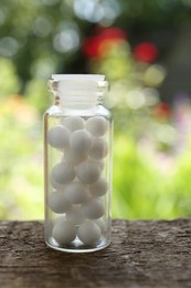 Bottle of homeopathic remedy on wooden table, closeup