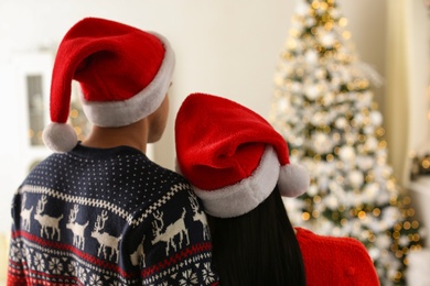 Couple in Santa hats at home, back view. Christmas celebration