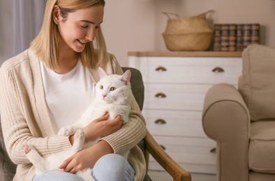 Young woman with her beautiful white cat at home. Fluffy pet