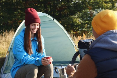 Tourists with mugs of coffee at campsite in morning