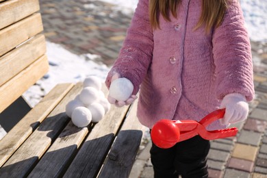 Little girl playing with snowball maker outdoors, closeup