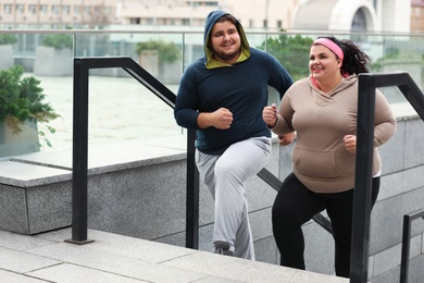 Overweight couple running up stairs together outdoors