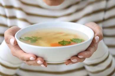 Young woman holding bowl of tasty soup, closeup