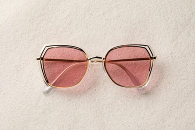 New stylish sunglasses on sand, top view