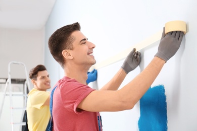 Male decorators working with tape indoors