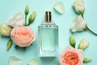 Flat lay composition with bottle of perfume and flowers on cyan background