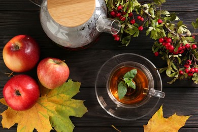 Hot tea, apples, dry leaves and viburnum on wooden table, flat lay. Autumn atmosphere