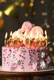 Beautiful birthday cake with burning candles on wooden stand