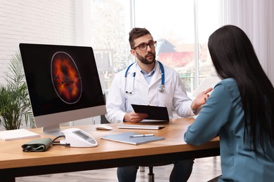 Neurologist consulting young patient at table in clinic