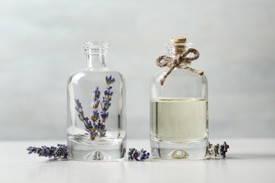 Photo of Bottles with natural essential oil and lavender flowers on white wooden table