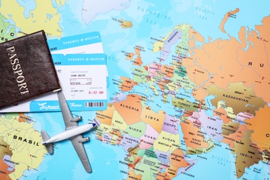 Toy airplane and passport with tickets on world map, flat lay. Space for text