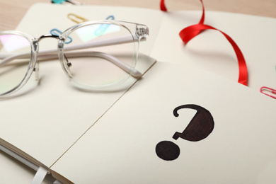 Question mark written in notebook and eyeglasses, closeup