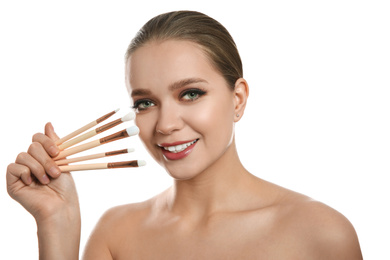 Beautiful woman with makeup brushes on white background
