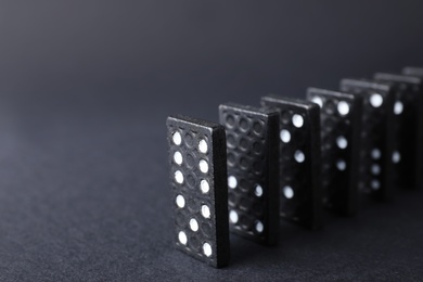 Domino tiles on black background, closeup. Space for text