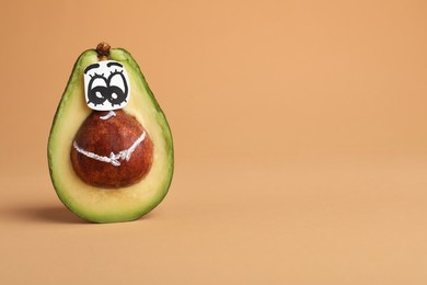 Photo of Avocado with drawn face on orange background, space for text. Exhibitionist concept