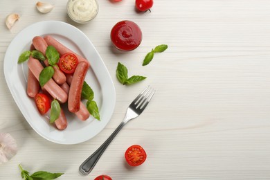 Delicious vegetarian sausages with basil, vegetables and sauces on white wooden table, flat lay. Space for text