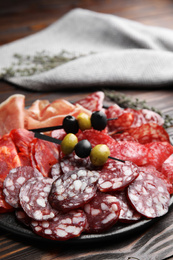 Tasty salami and other delicacies on wooden table, closeup