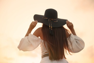 Photo of Young woman in hat at sunset, back view
