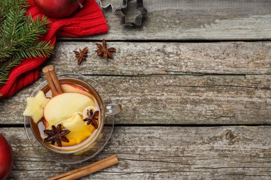 Hot mulled cider and ingredients on wooden table, flat lay. Space for text